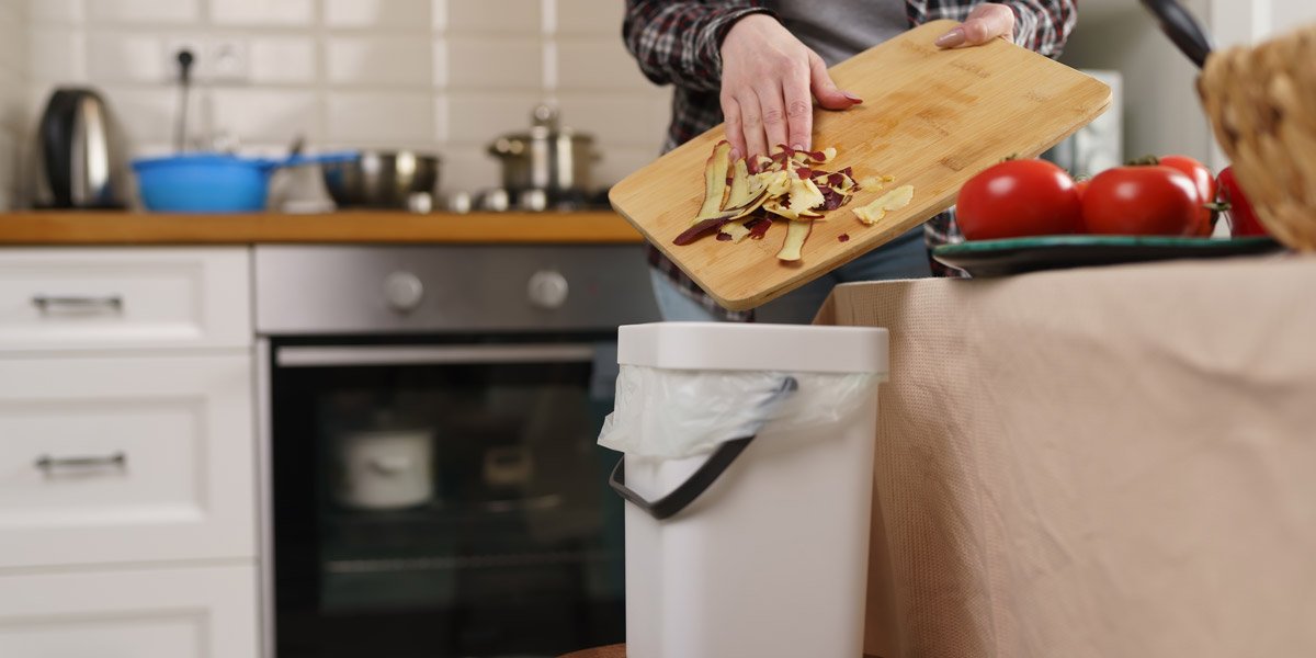 Female person throwing compostable food leftovers in a bokashi bin. Housewife recycling organic waste in a compost bin in a home kitchen.